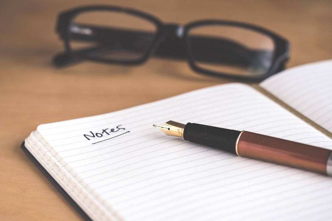 notepad with a pen and glasses